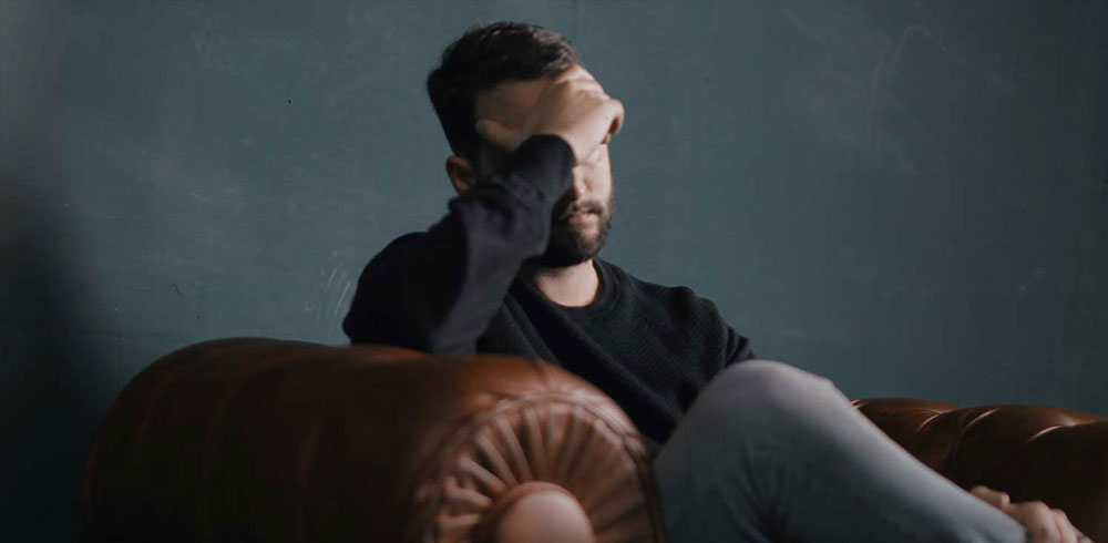 Man holding head on couch